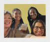 Selfie Image of four women smiling and holding a box of cards from My Neighbors Voice